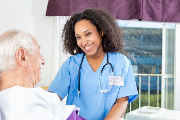 Caregiving nurse happy with elder patient in hospital bed Caregiving nurse happy with elder patient in hospital bed